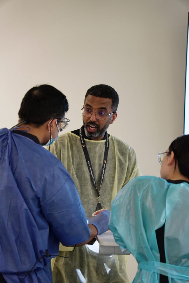 Dental instructor talking with trainees in protective gowns
