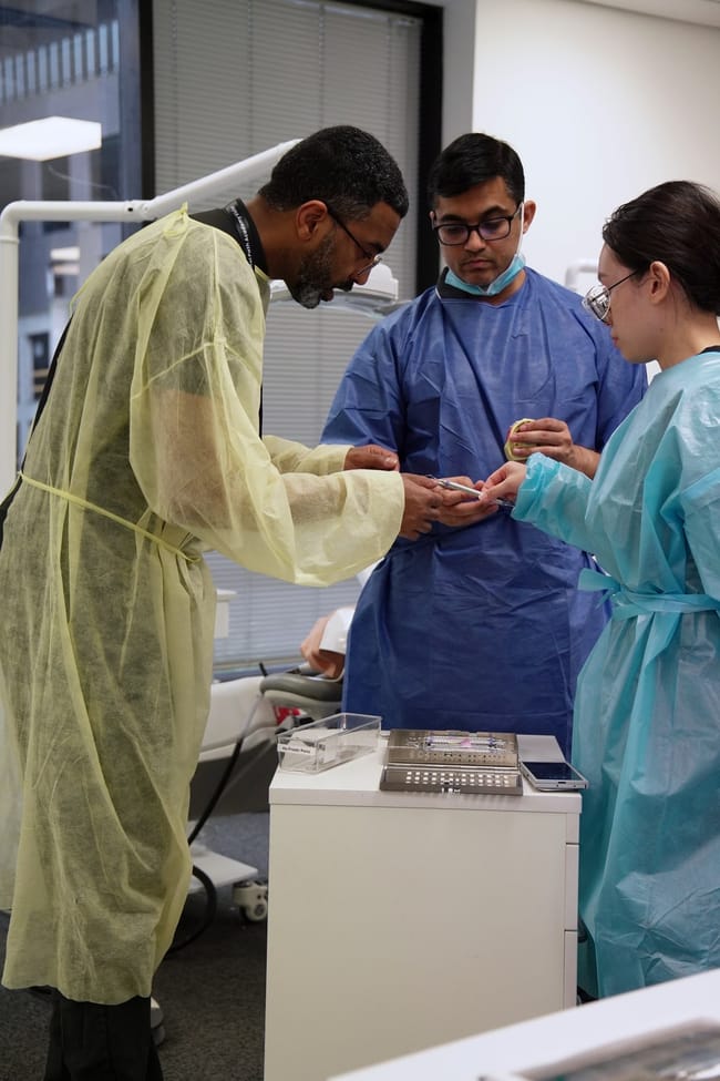 Instructor demonstrating a technique to two dental trainees